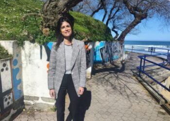 Laura Velasco, portavoz del Grupo Municipal VOX en el Ayuntamiento de Santander, posando en los Jardines de Piquío con el mar Cantábrico y grafitis en las paredes de fondo, en un día soleado.