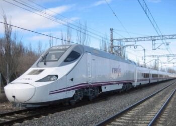 Tren de alta velocidad de Renfe circulando por una vía electrificada en un entorno rural, con árboles sin hojas al fondo y cielo despejado.
